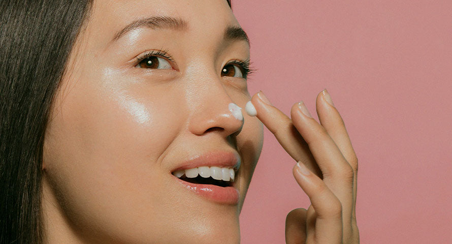 Woman applying moisturizing cream to her face, sealing in hydration for soft and supple skin.