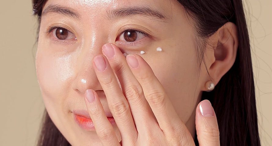 Woman gently applying eye cream under her eyes, targeting dark circles and fine lines.