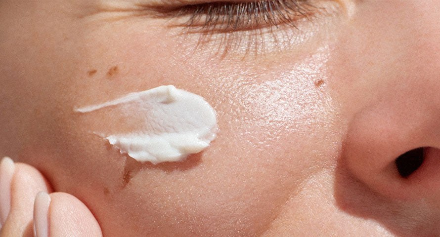 Close-up of a woman applying cream to her cheek, highlighting the delicate action of nurturing and protecting the skin with moisturizer.