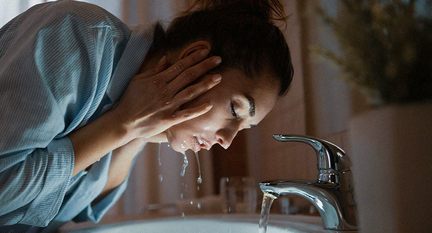 Woman gently washing her face, capturing the essential first step in a skincare routine focused on achieving clean, refreshed skin.