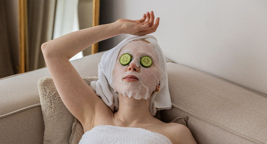 Woman relaxing with a facial mask and cucumber slices over her eyes, illustrating a self-care routine for skin health and rejuvenation.