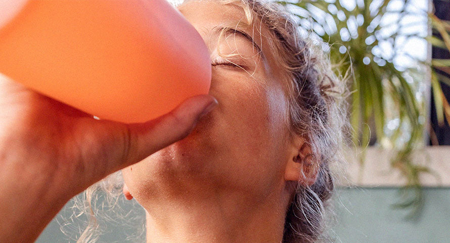 Close-up image of a woman drinking water from a clear glass, highlighting her hydration and healthy lifestyle.