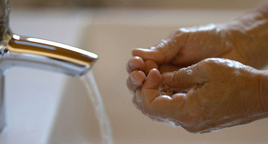 Close-up of hands being meticulously washed under running water, underscoring the significance of cleanliness for skin health and overall hygiene.
