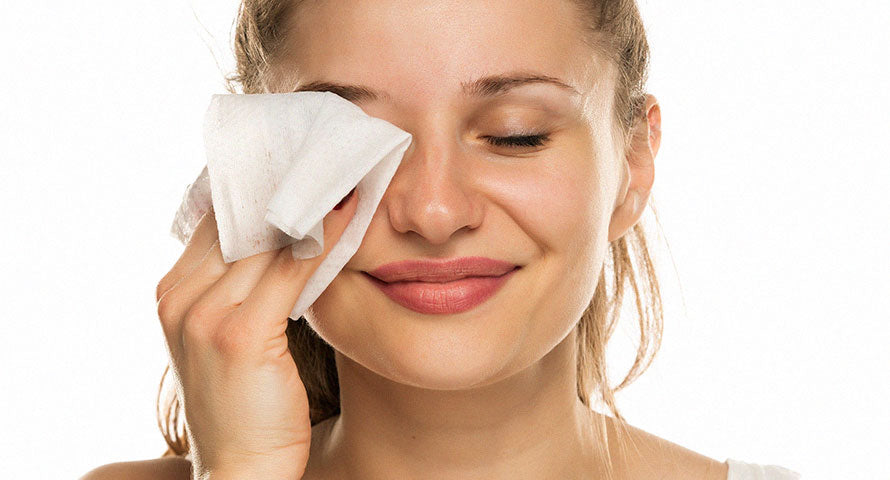 Woman gently cleansing her skin using a facial cleansing pad, illustrating a crucial step in a thorough skincare routine for maintaining healthy, radiant skin.