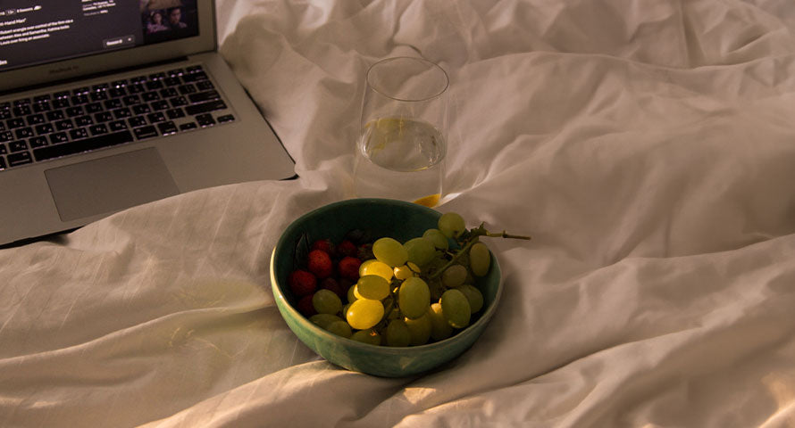Image of fresh fruit and a glass of water beside a laptop, representing a healthy lifestyle balance of nutrition and productivity