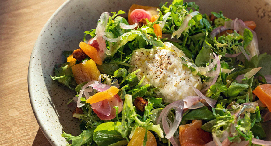 Fresh, vibrant bowl of mixed green salad with various vegetables, topped with seeds.