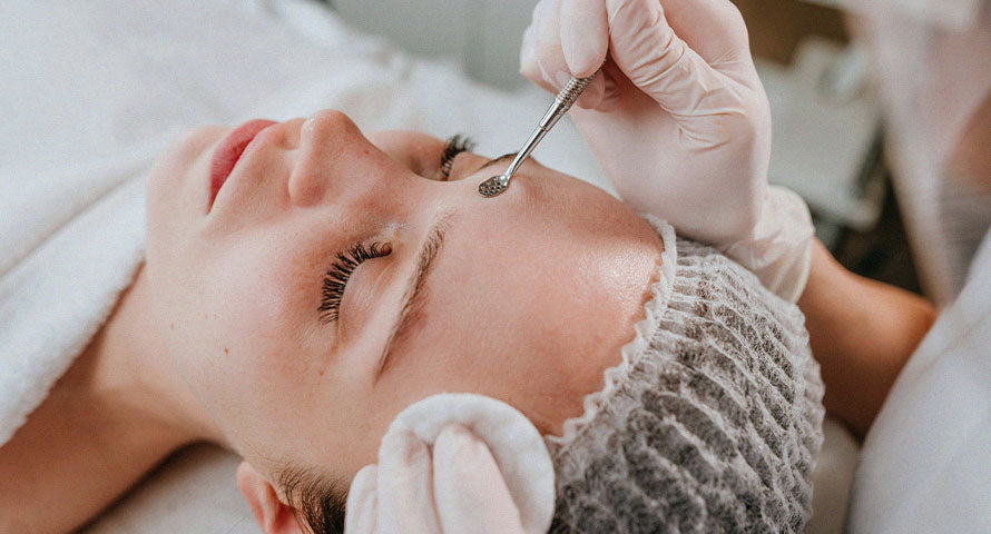 Woman enjoying a calming spa session, with a focus on facial treatment, in a tranquil spa setting.