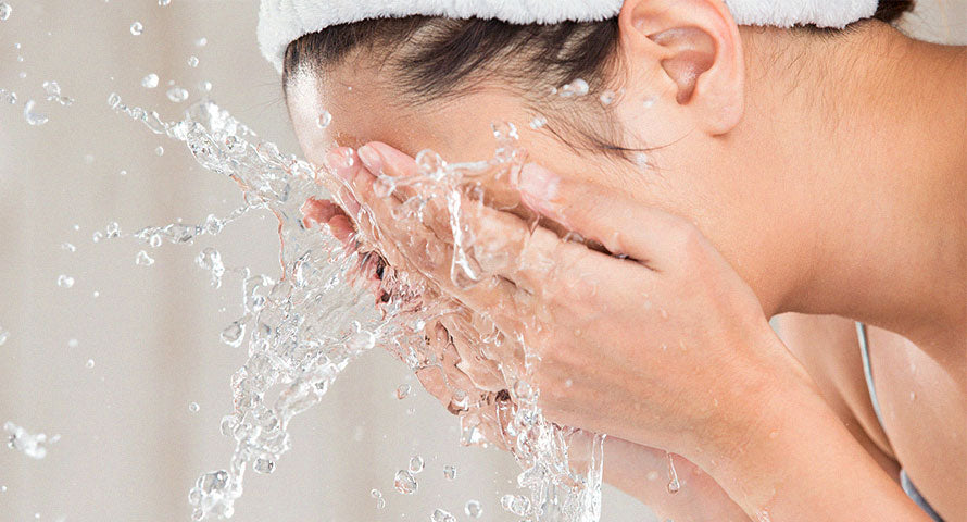 Woman gently splashing water on her face as part of her skincare routine.