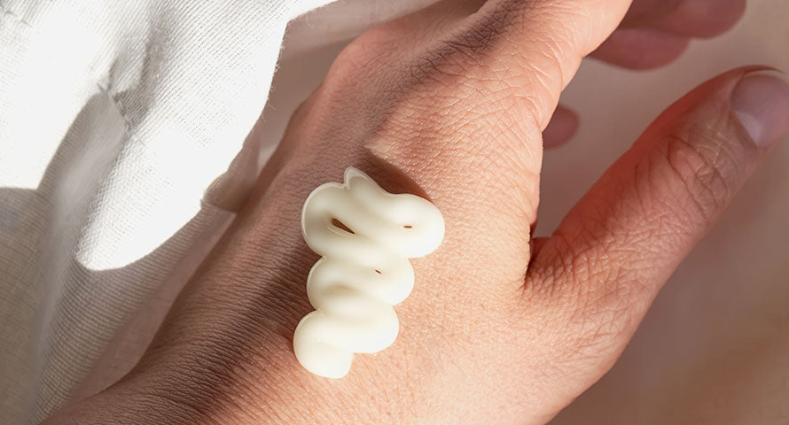 Close-up image of a hand with a dollop of cream on it, focusing on the creamy texture and detailing how the product sits on the skin, illustrating its consistency and potential moisturizing benefits.