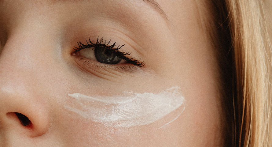 Close-up image of a person's face with eye cream gently applied under the eye, showcasing the cream's texture and the application technique to emphasize skincare routine details.