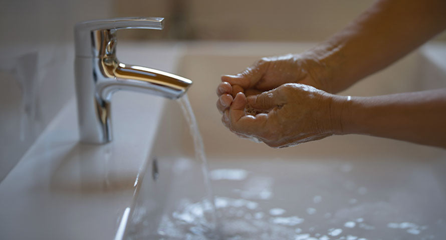 Image of hands being washed under a running tap of water, demonstrating proper skincare hygiene while highlighting the importance of conserving water as part of an eco-friendly skincare routine.