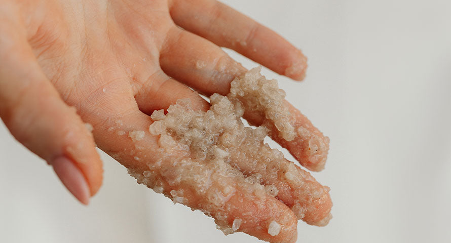 Image of a hand with a sugared texture applied, showcasing a DIY sugar scrub used for exfoliating the skin, emphasizing the coarse texture and natural composition suitable for skincare.