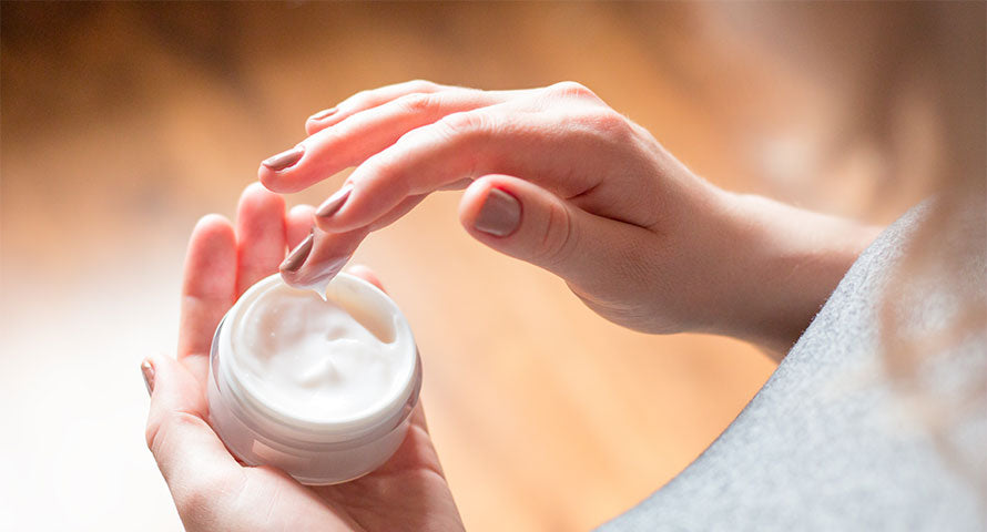 Close-up image of a hand dipped into a jar of cream, testing the texture with fingertips to demonstrate the cream's consistency and richness, highlighting an essential step in evaluating skincare products.