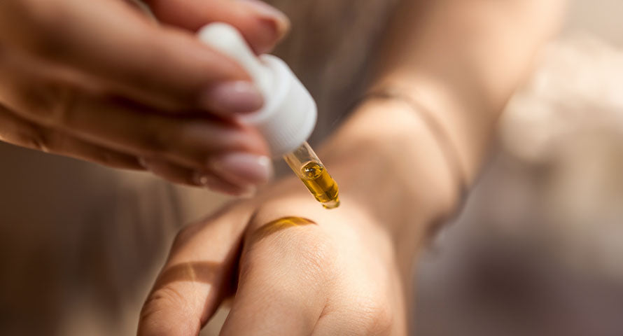 Close-up image of a woman's hand applying serum to her other hand, highlighting the serum's texture and the application process, emphasizing skincare routine and product efficacy.