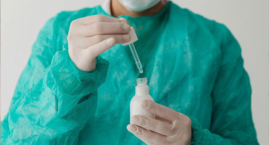 Image of a person in a laboratory holding a vial of serum, wearing protective lab gear including gloves and a lab coat, showcasing a scientific research environment.
