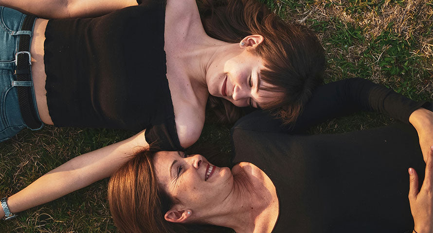 Mother and daughter lying side by side, smiling joyfully at each other.