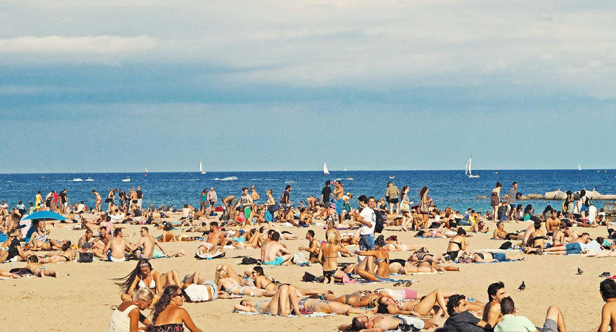 Aerial view of a bustling beach packed with vacationers under the summer sun.