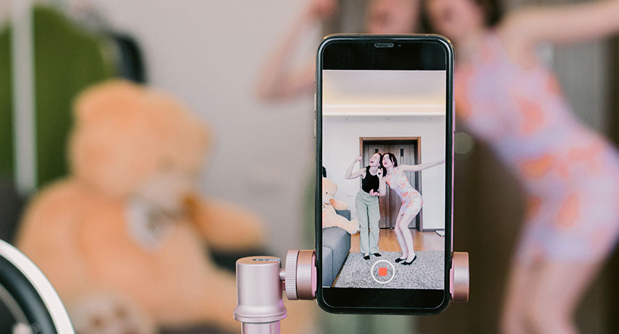 Image of a mobile phone displaying a recording of two women, representing the trend of sharing beauty routines and tips on social media platforms.