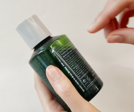 A GIF showing a person peeling off the label from a Blithe Patting Splash Mask - Soothing and Healing Green Tea bottle and placing the bottle in a recycling bin, illustrating the ease of Blithe's eco-friendly packaging practices.