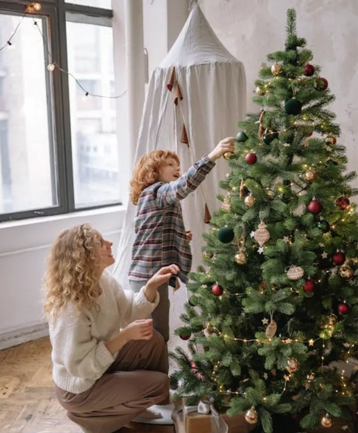 Child with mom decorating a Christmas tree