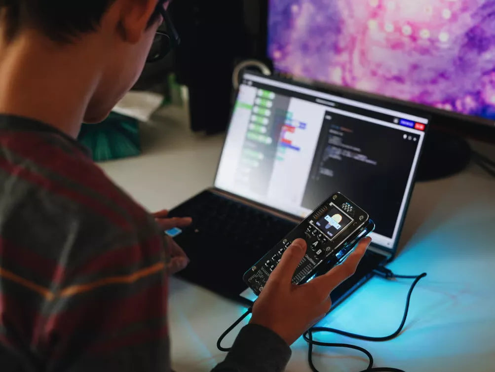 Kid programming a DIY mobile phone on a laptop