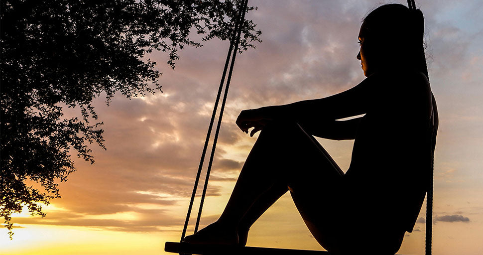 Silhouette of contemplative woman looking at sunset to represent accepting the unknown