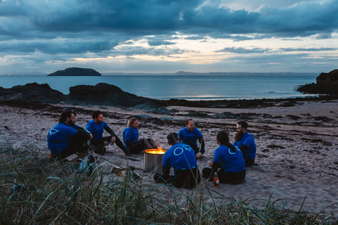 team of adventurers sat around a campfire on the beach