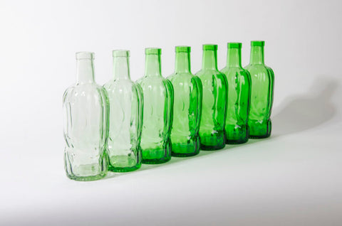 Row of River Rock whisky bottles using recycled glass in various shades of green