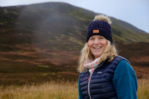 Blonde woman smiling whilst standing in front of hills, laura co-founder of river rock whisky