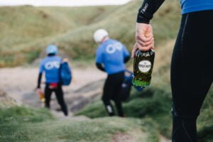 Three males hiking on a  Scottish hill, one holding a bottle of River Rock single malt whisky