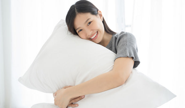 smiley face girl with a white pillows expressing the happiness with prolong lifespan