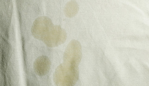 body oil stains over the white bamboo bedsheets