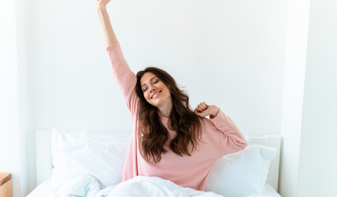 A young girl expressing her good sleep after taking the most affordable bamboo sheets