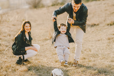 A little boy playing with a soccer ball and his parents
