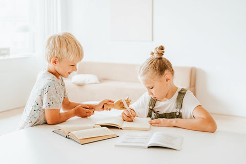 A young girl and boy reading books together