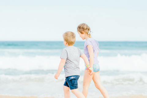Two kids walking hand in hand at the beach