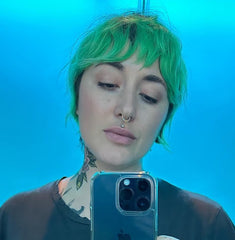 person with short green hair taking a selfie