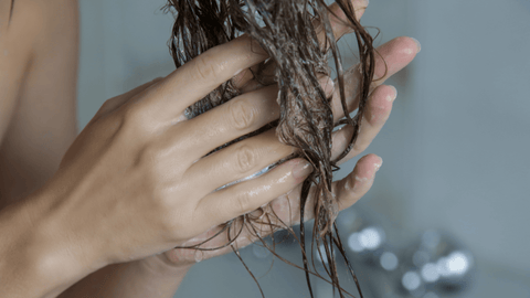 Woman massaging split ends in shower