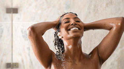 Woman smiling while washing hair in shower