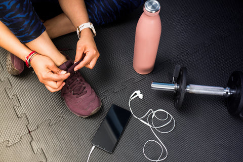 A picture of a woman tying her shoes on foam gym mats