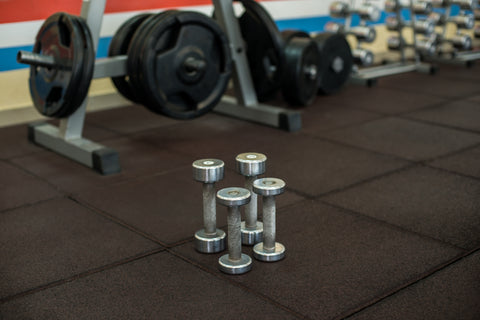 A picture of small dumbbells on top of rubber gym floor mats