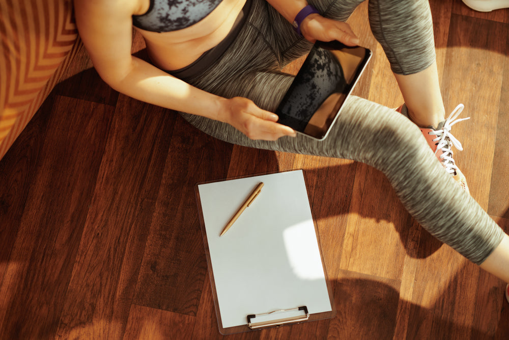 A picture of a woman using an Ipad to track her exercise progress