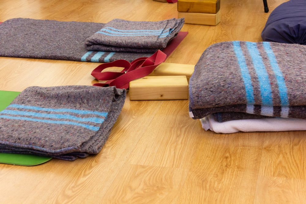 Grey yoga blankets set out on yoga mats and blocks