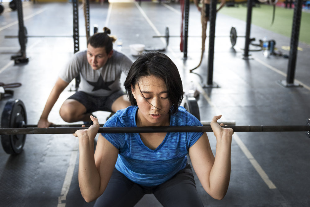 A picture of a woman using a barbell to front squat.