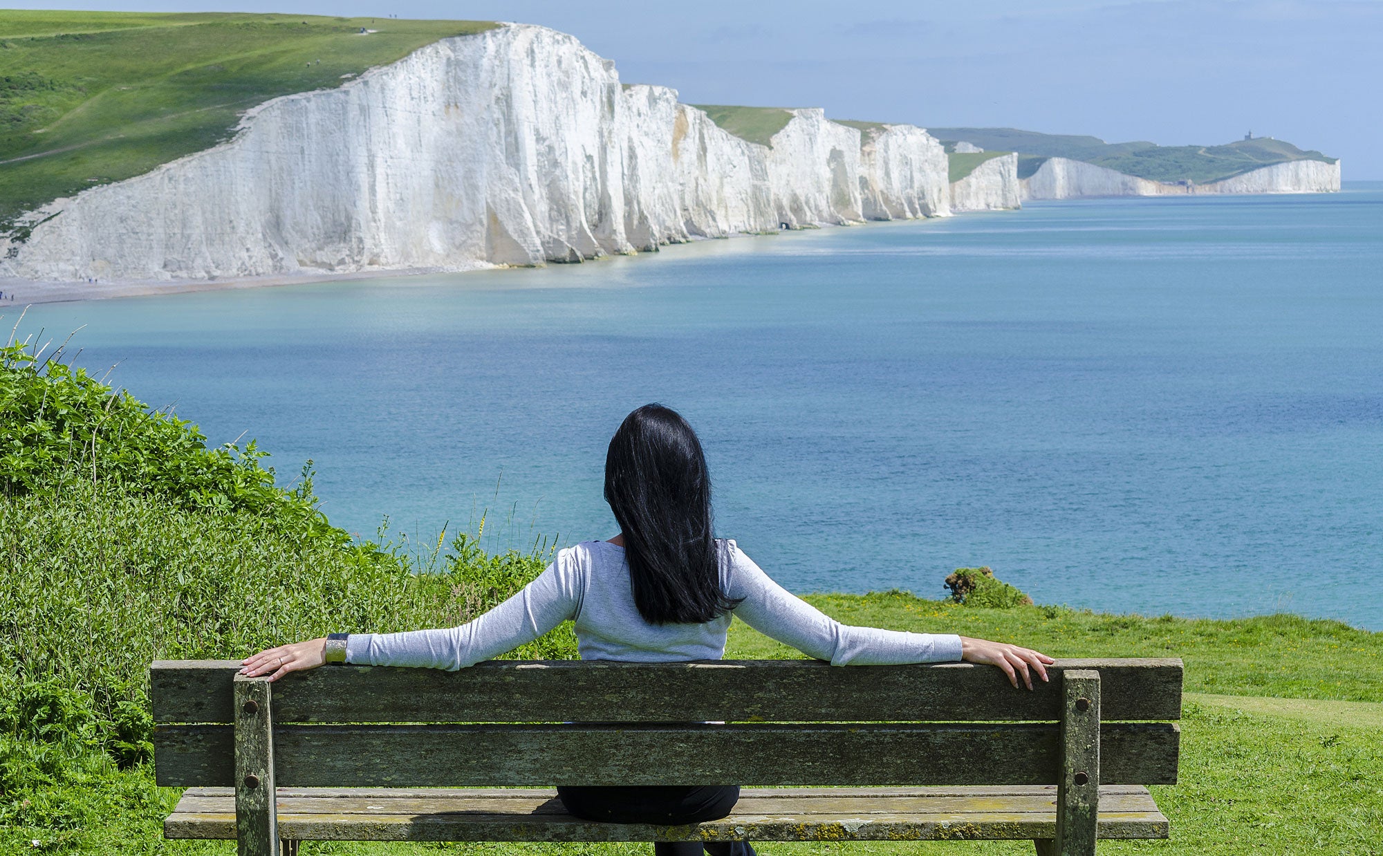 Woman relaxing on a bench with cliffside view
