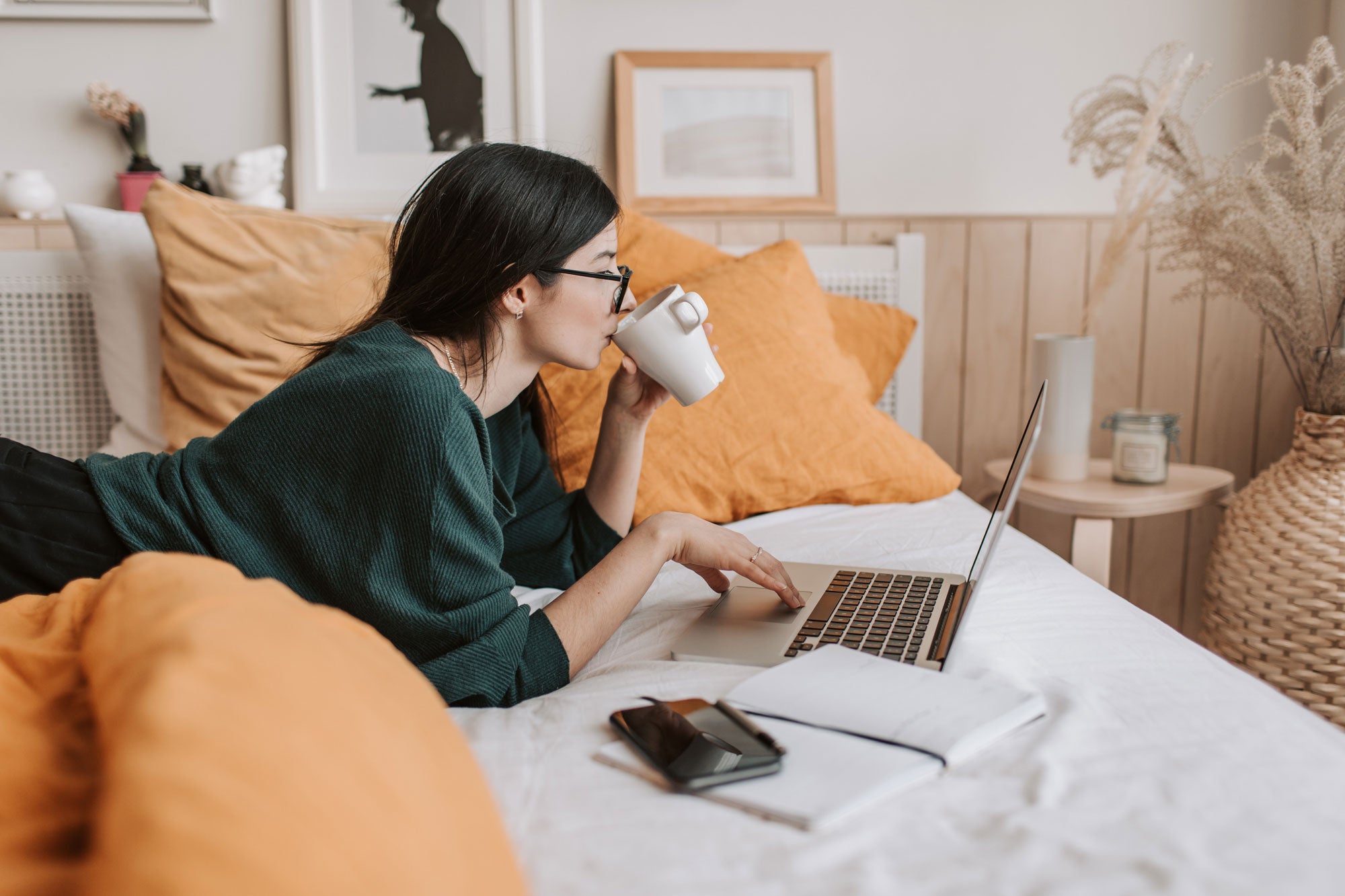 woman in bed watching news on her MacBook Pro