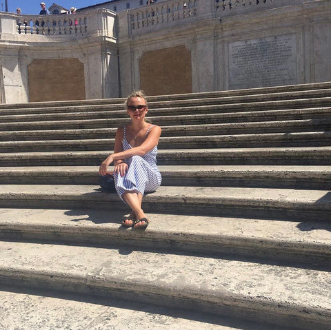 A lady sitting on some steps abroad.