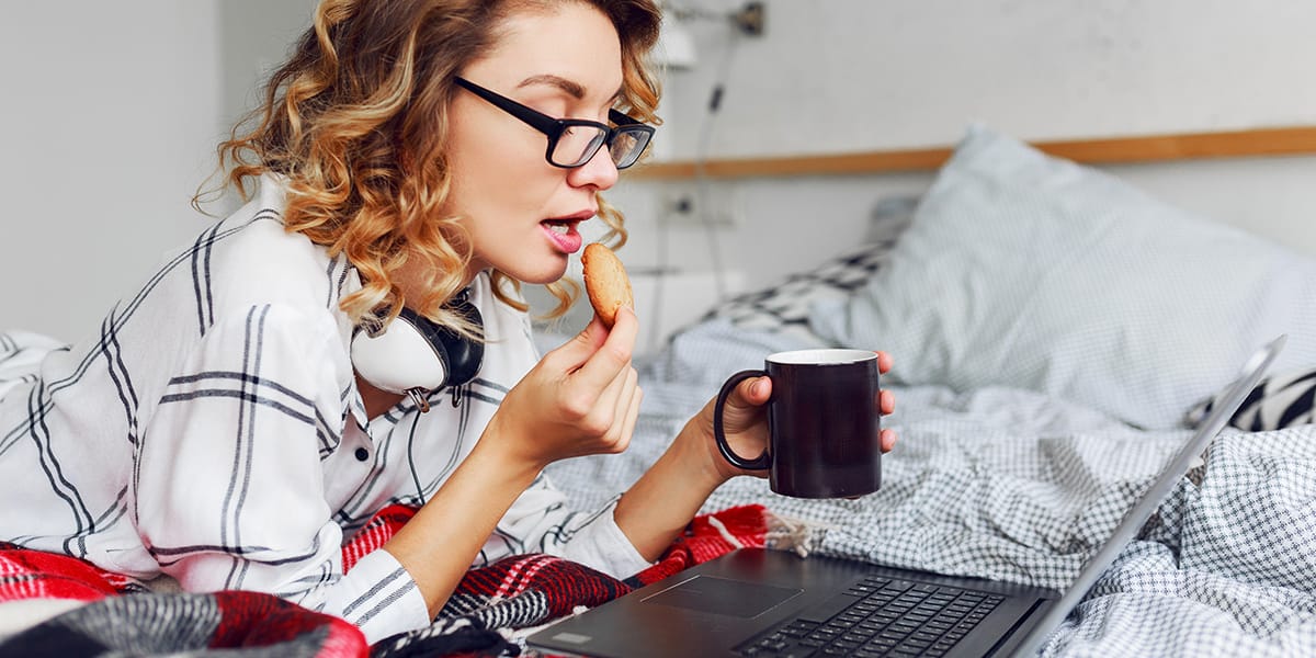 Lady eating a biscuit and searching online during lockdown