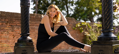 Simone smiling at the camera in gym wear, sitting on a wall