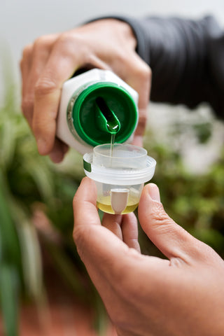 Liquid fertiliser being poured into cap from bottle